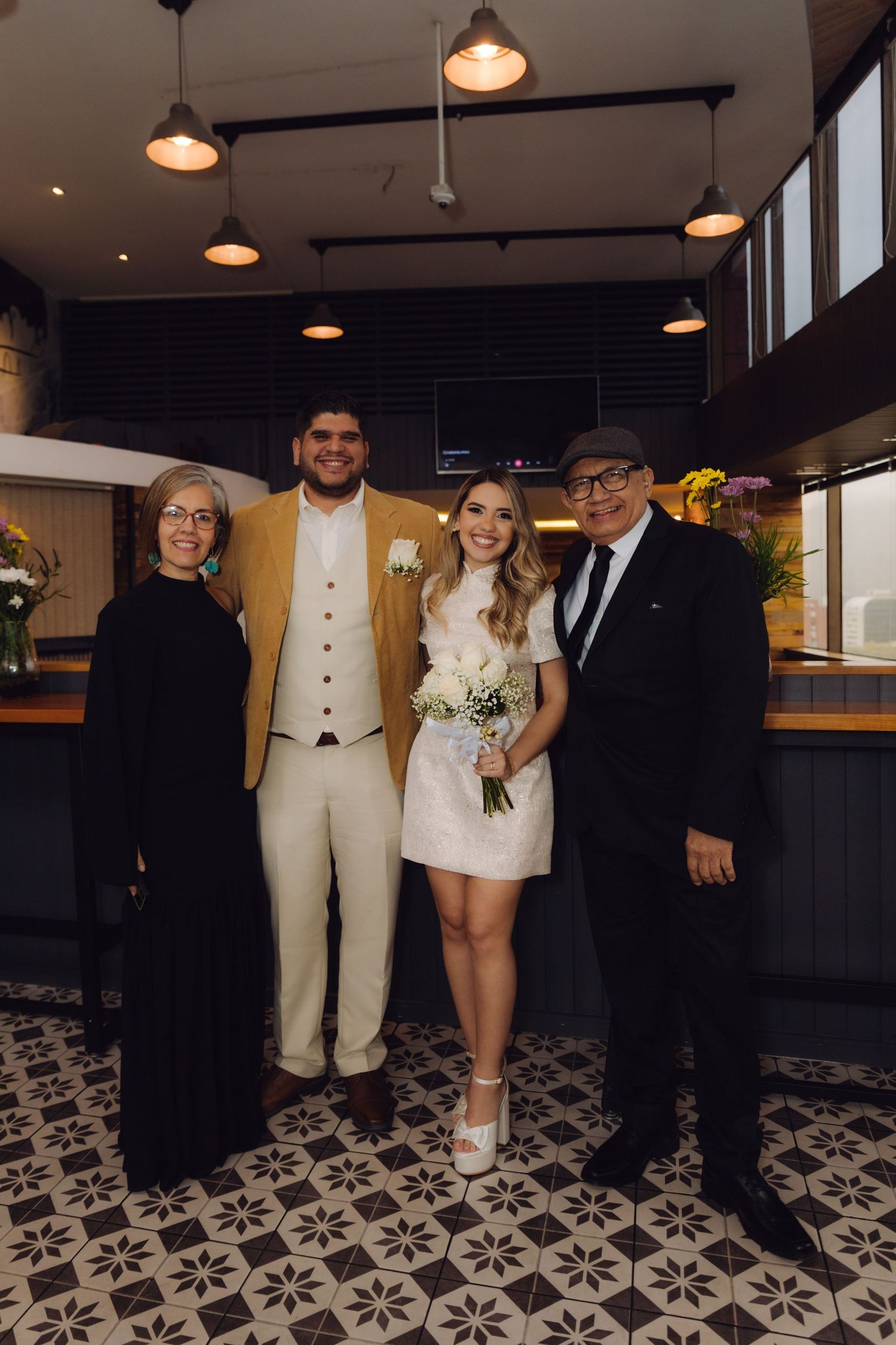 Couple in wedding attire poses with older family members in a modern restaurant venue.