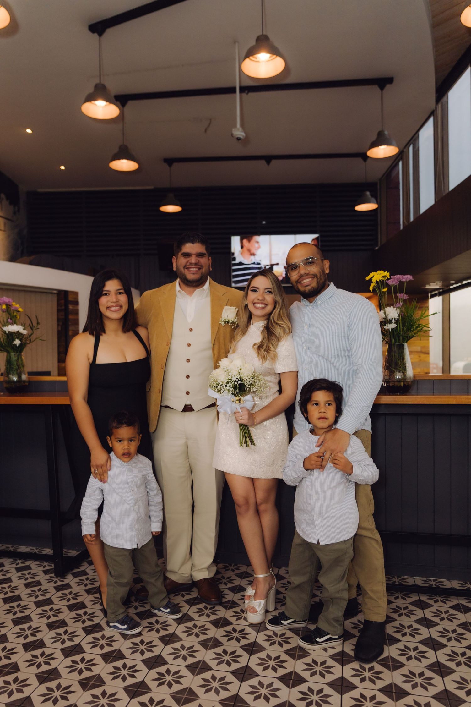 Bride and groom celebrate with family including two young children at wedding reception.