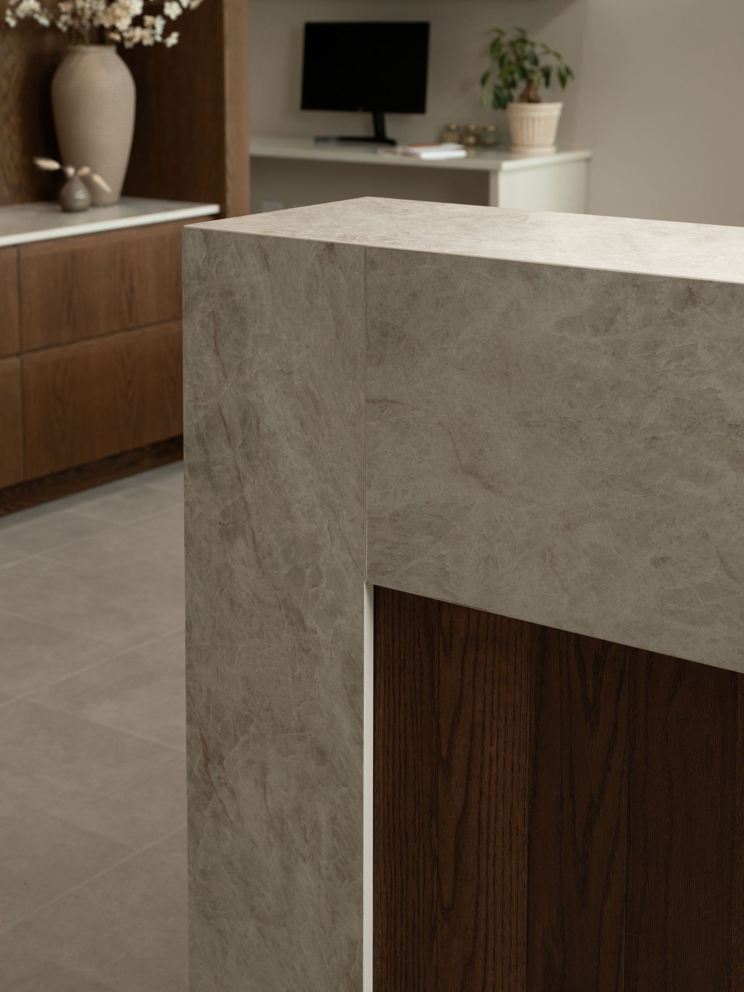 Modern kitchen island with gray stone countertop and warm walnut wood panel detail in a contemporary interior.