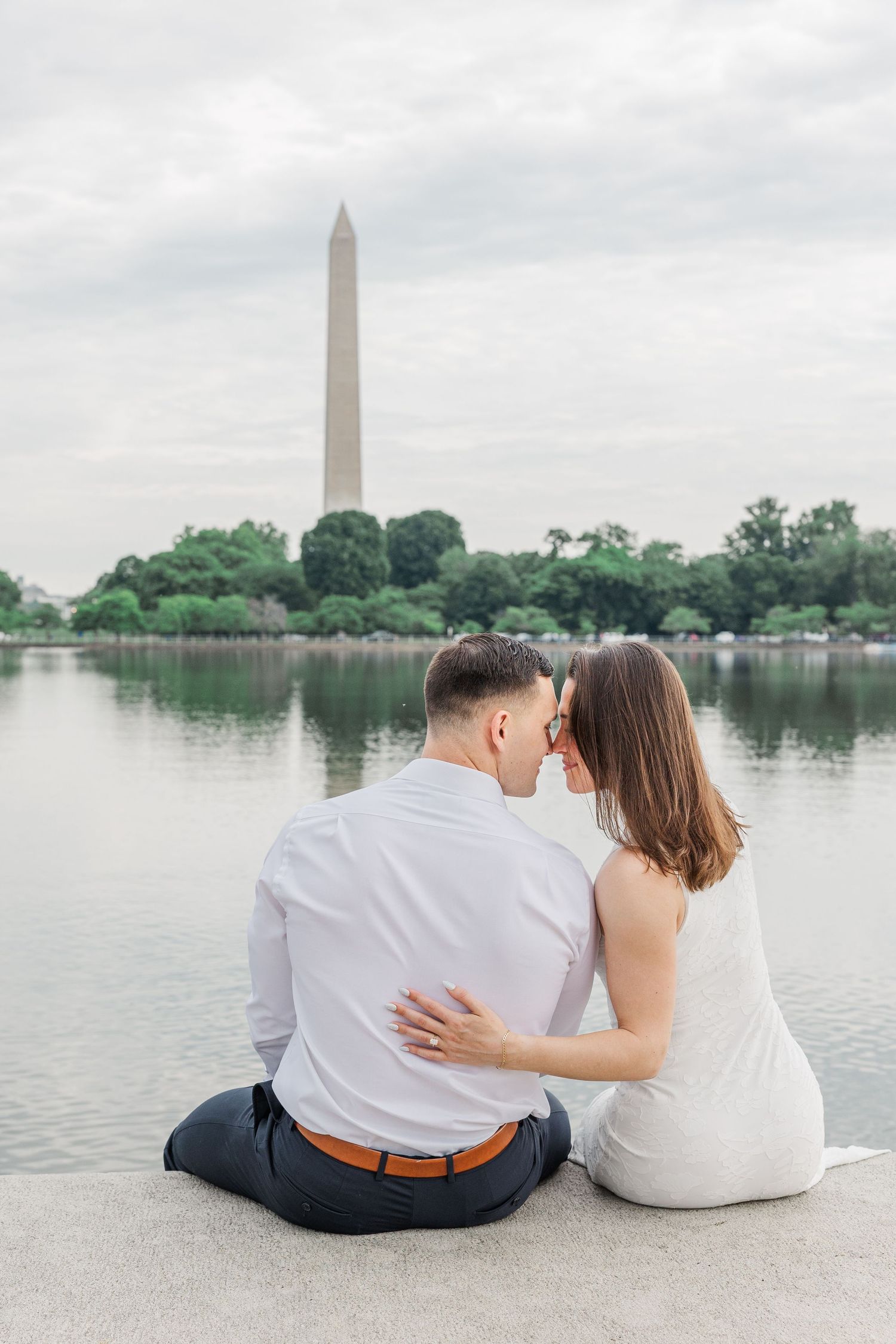 Couple sitting together near the Tidal Basin with the Washington Monument in background.