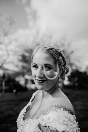 A close-up portrait of a bride wearing a lace wedding dress outdoors.