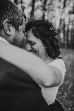 Black and white intimate portrait of newlyweds sharing a joyful moment in the woods.