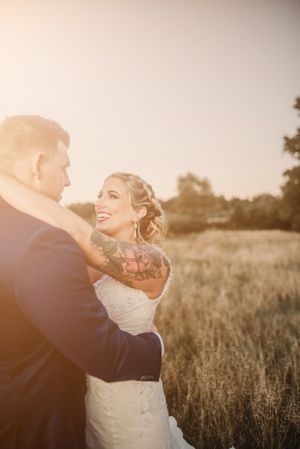 Newlyweds sharing joyful moment in sunlit field at golden hour.