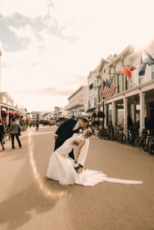 Dramatic wedding dip kiss on a historic main street with American flag in background.
