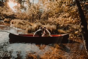 Romantic couple sitting in canoe during golden autumn sunset.
