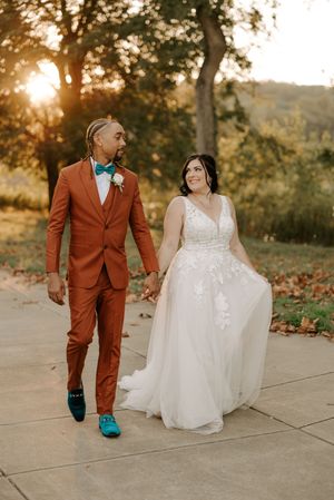 Wedding couple walking together, groom in striking rust-colored suit with turquoise shoes.