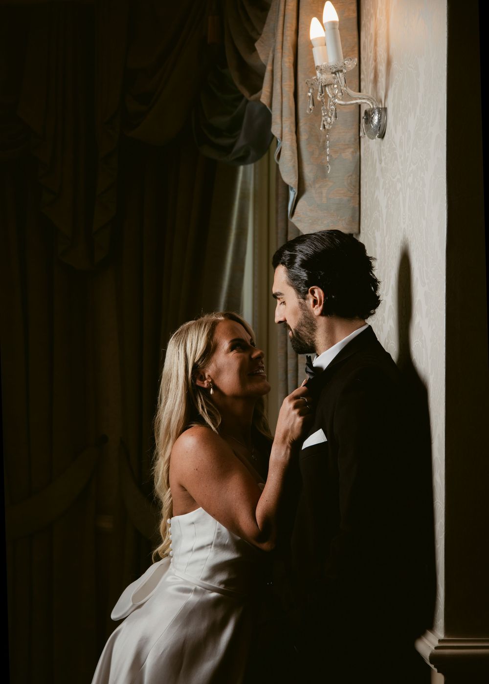 Bride and groom share a romantic moment by candlelight in a dimly lit elegant venue.