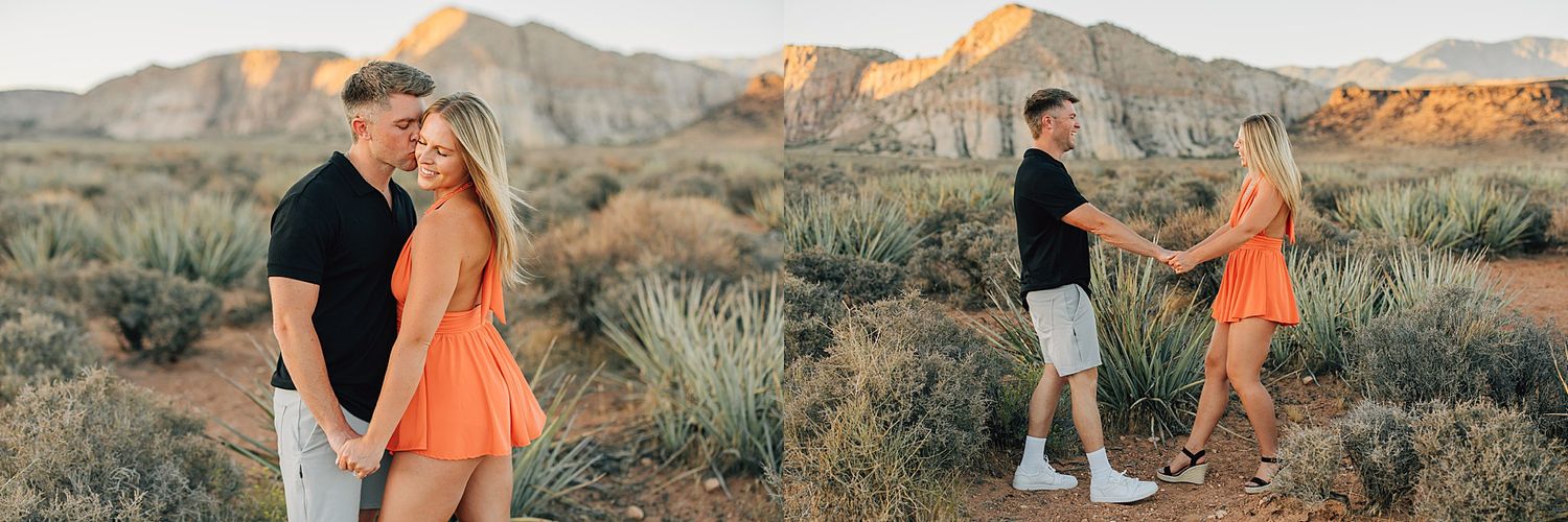 Couple embracing in desert landscape at golden hour, woman in orange dress, red rock formations in background.