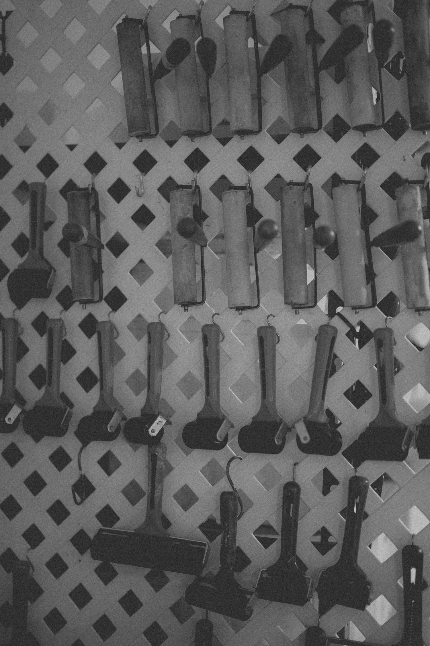 Black and white image of woodworking hand planes arranged on pegboard wall.