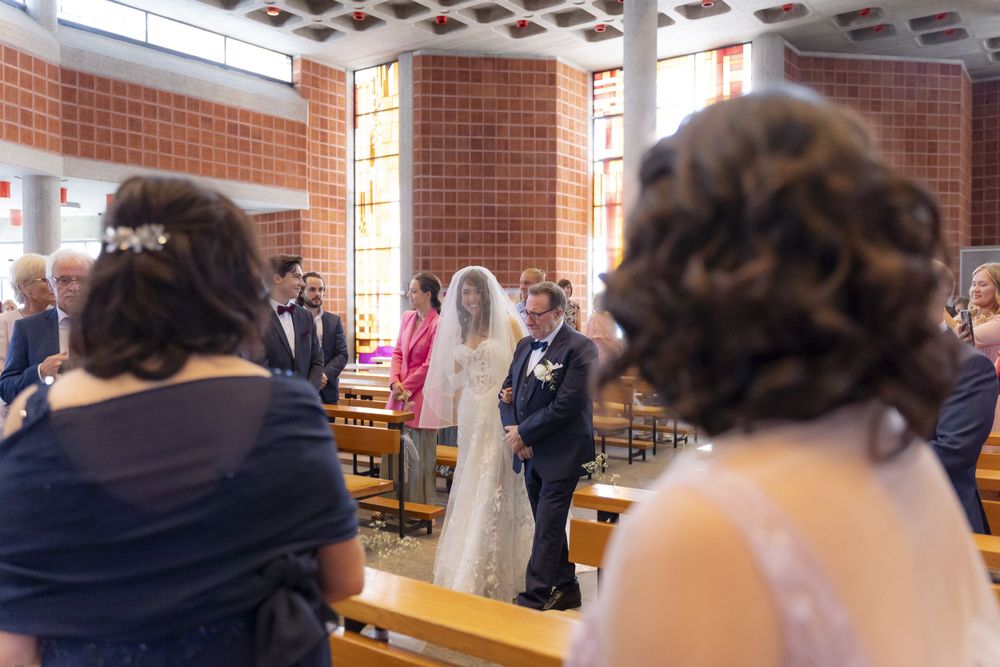 Bride and groom walking down church aisle during wedding ceremony with guests seated.