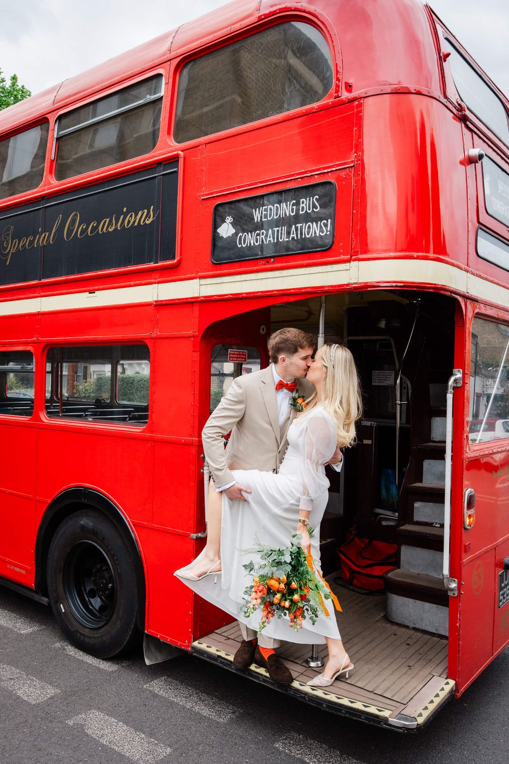 Red London bus wedding bride and groom kissing on the bus
