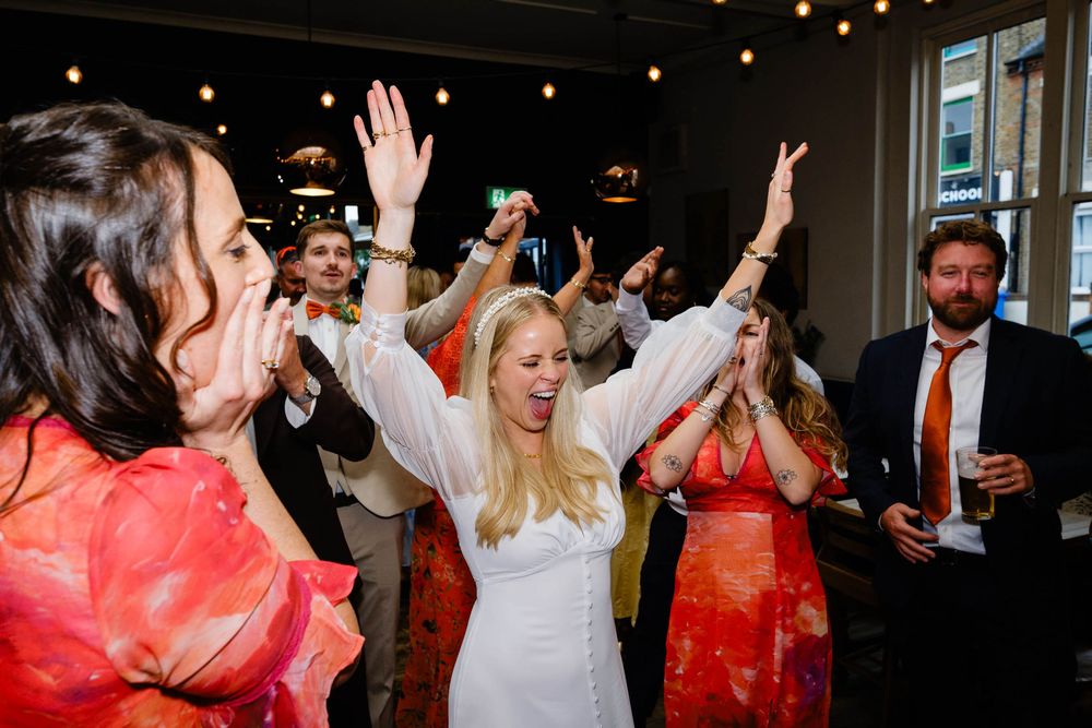 bride cheering at wedding on the dance floor while having a great time