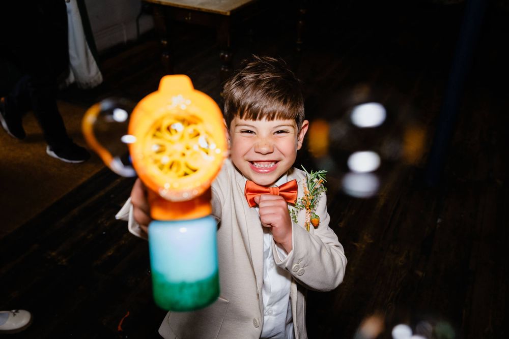 page boy with bubble gun at London wedding laughing