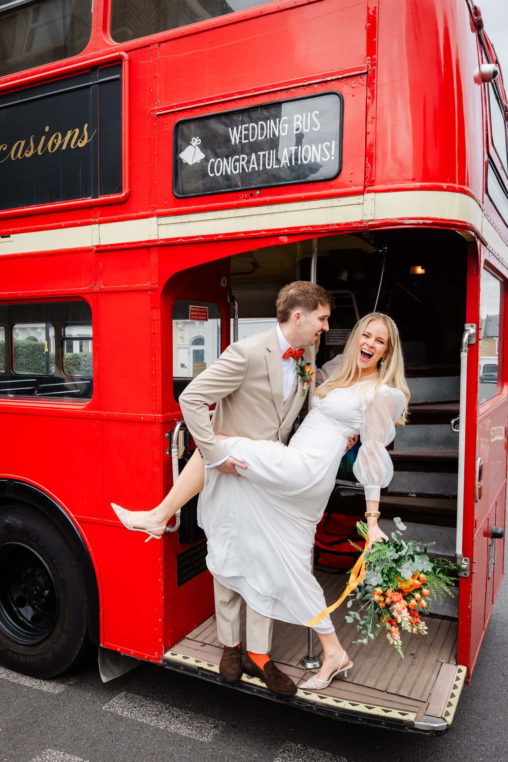 bride and groom doing a dip kiss on red London wedding bus