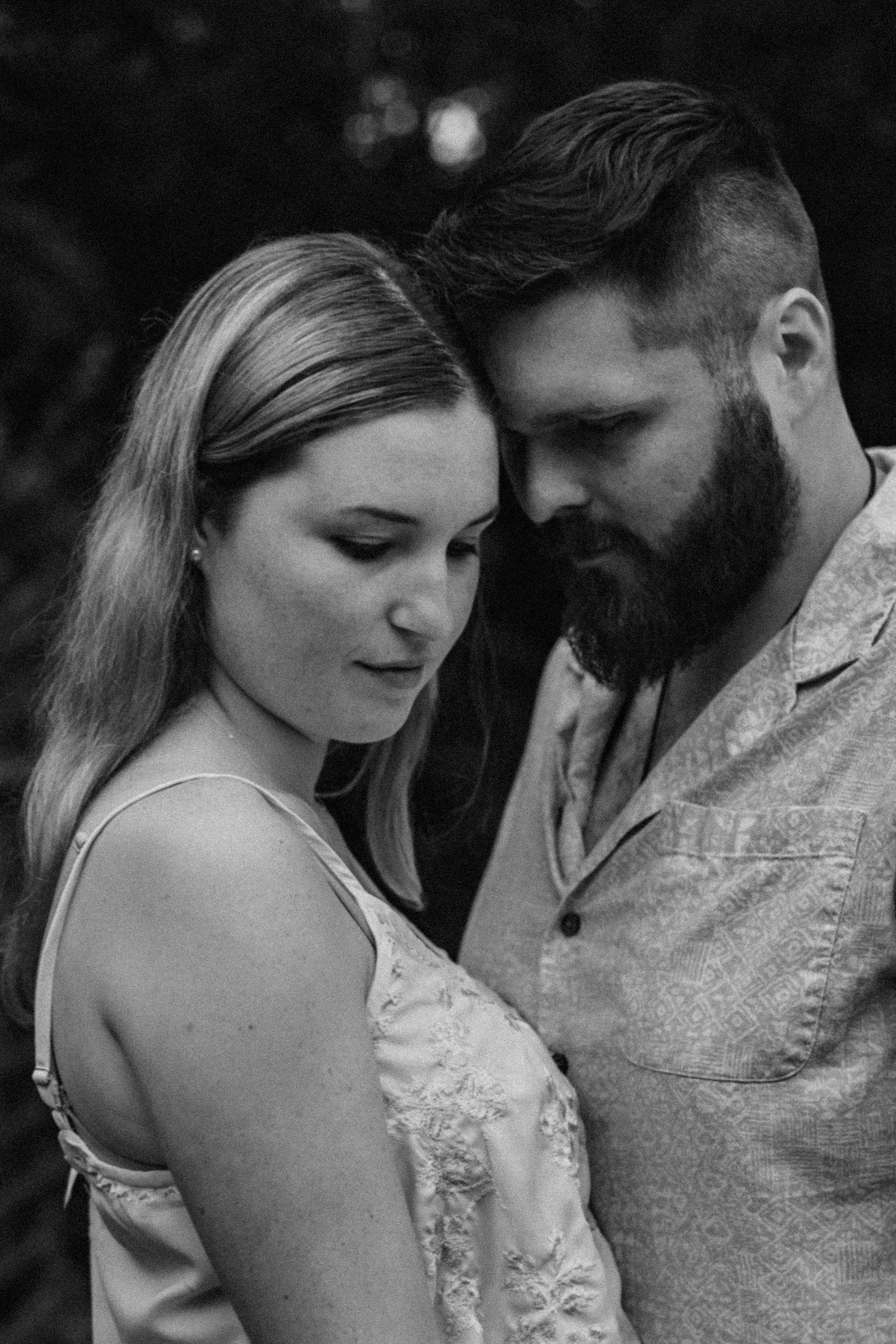 Black and white portrait of a couple in an intimate embrace, bearded man and blonde woman sharing a tender moment.