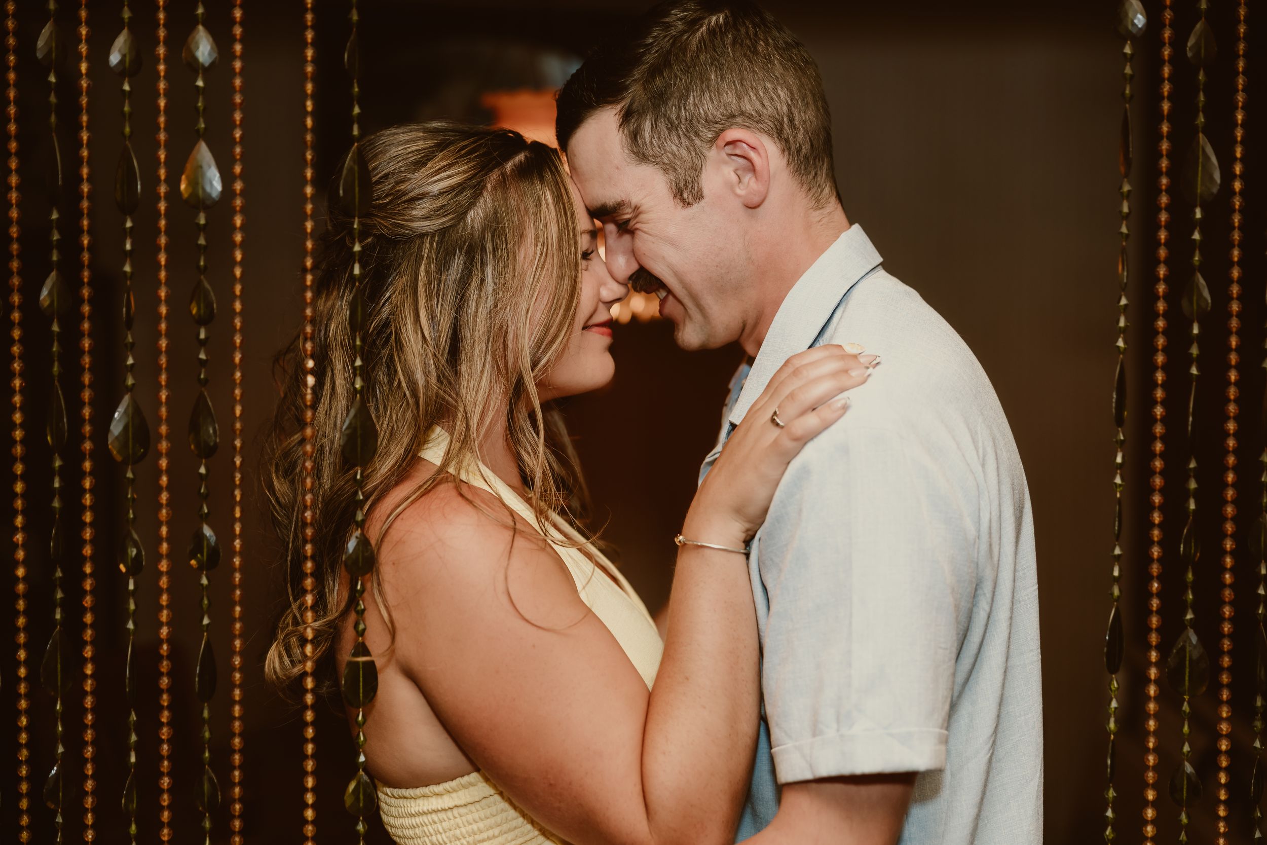 A couple shares a joyful, intimate moment laughing together at a romantic evening event.