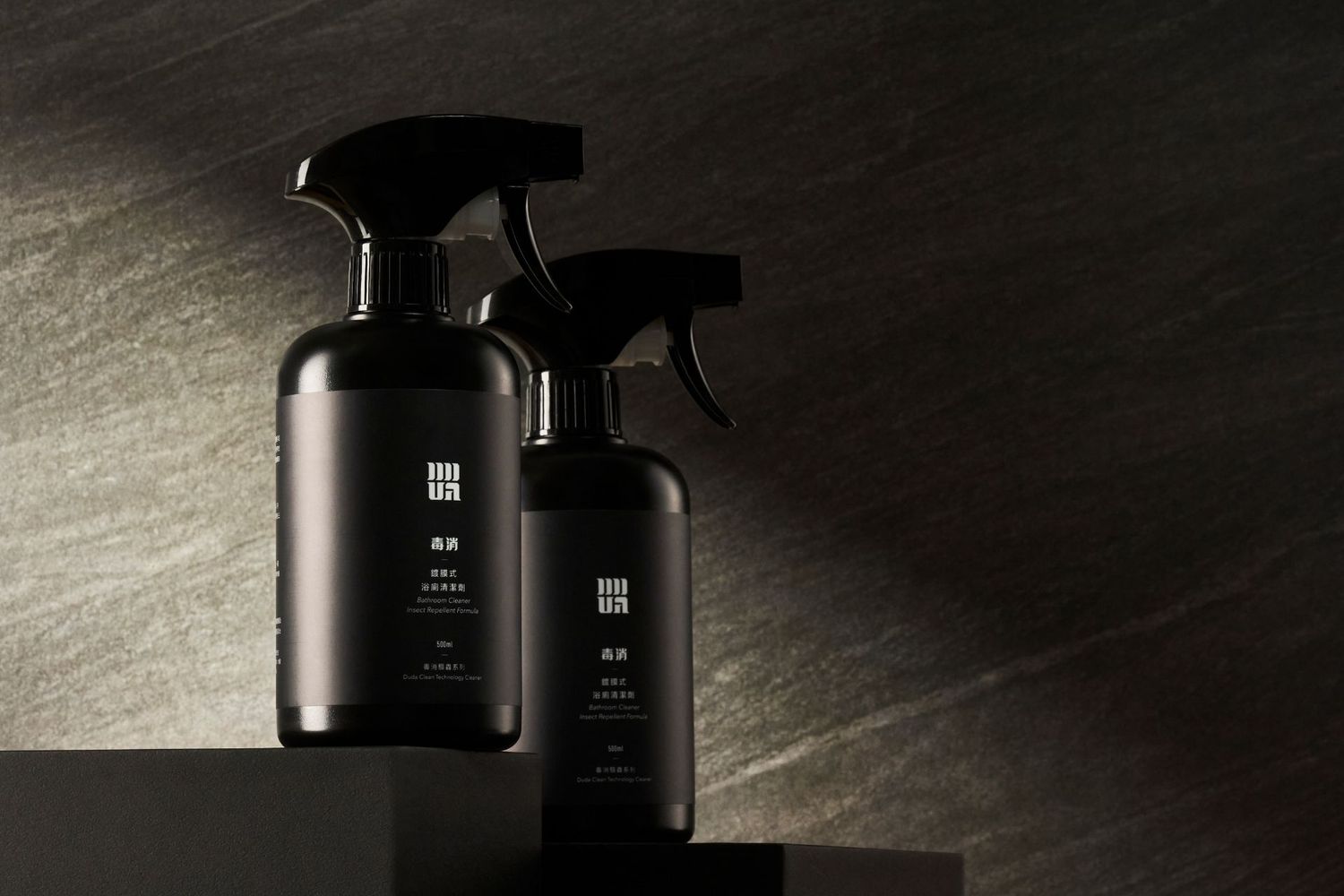 Black spray bottle of Japanese cleaning solution displayed on a dark surface with dramatic light beam in background.