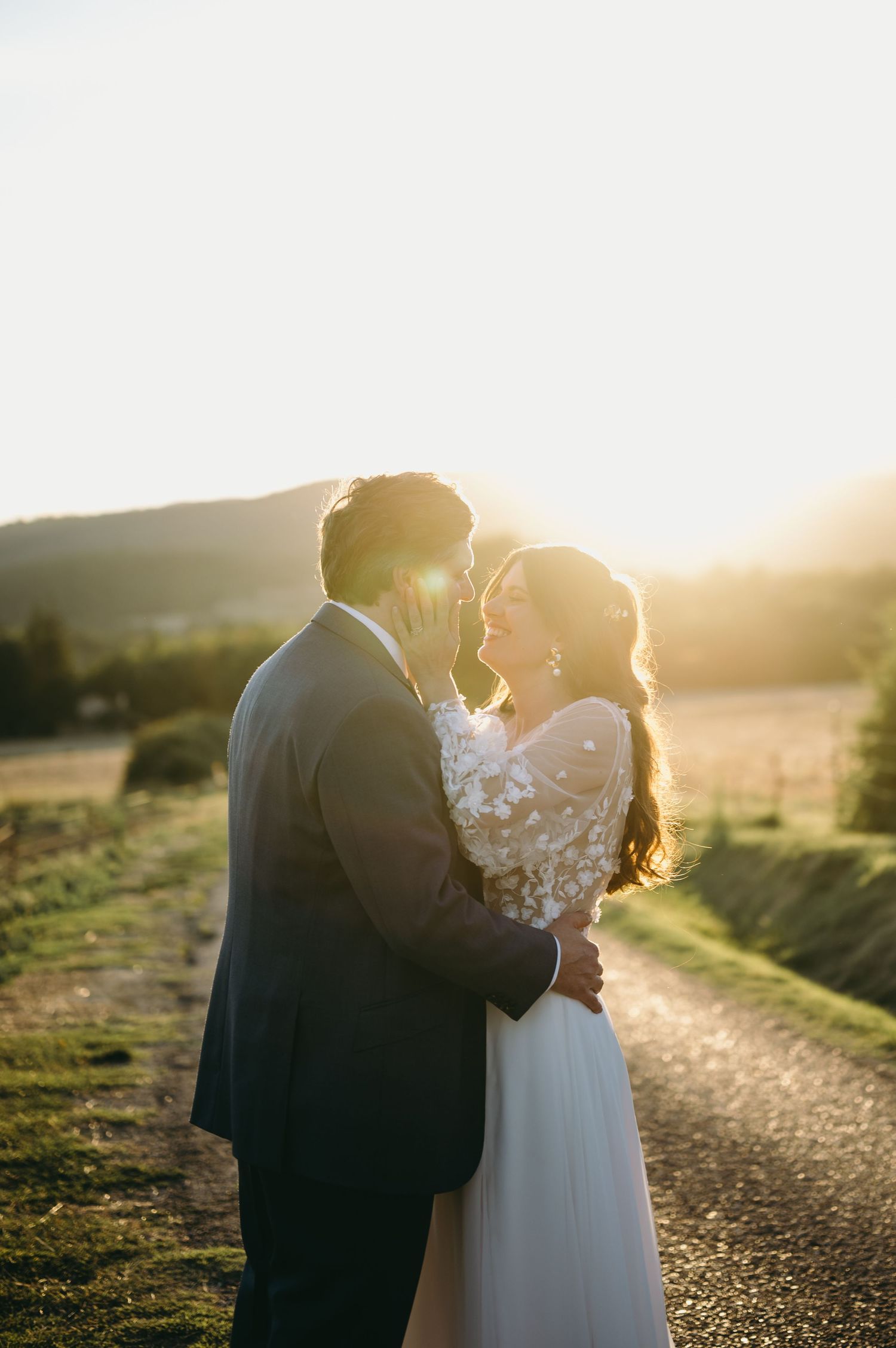 Golden hour wedding portraits with sunlight creating a romantic backlit glow on a hilltop path.