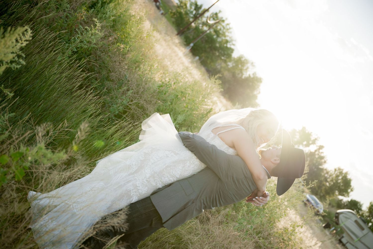 A bride in a flowing white dress runs through a sunlit garden path while holding her gown.