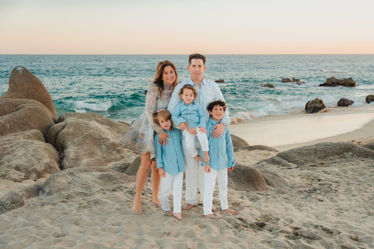 Happy couple embraces and laughs together during sunset photoshoot at the beach.