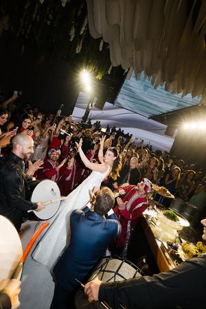 Energetic crowd at a concert venue with dramatic lighting and hanging fabric decor overhead.