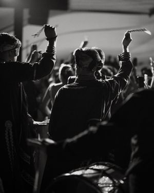 Silhouetted crowd with raised hands at a concert or nightclub event with dramatic lighting.