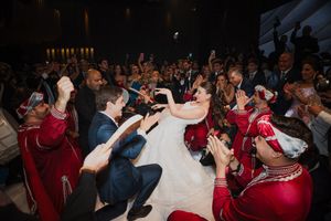 A crowd of people in red and dark clothing gather at an indoor event space during a celebration.