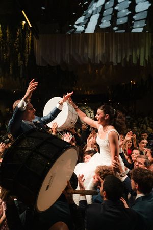 Concert crowd surges forward in dark venue with dramatic lighting as performers energize the audience.