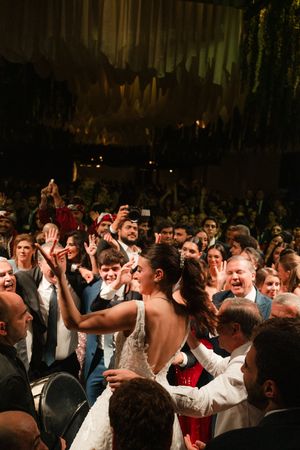 A lively crowd of wedding guests dancing and celebrating together on a dark dance floor at a reception party.