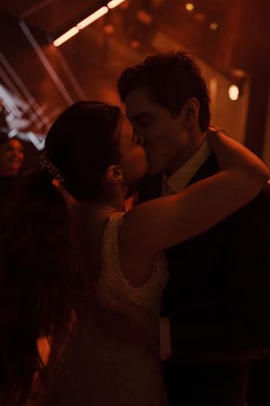 A silhouetted couple dances intimately in a dimly lit room with warm orange lighting creating a romantic atmosphere.