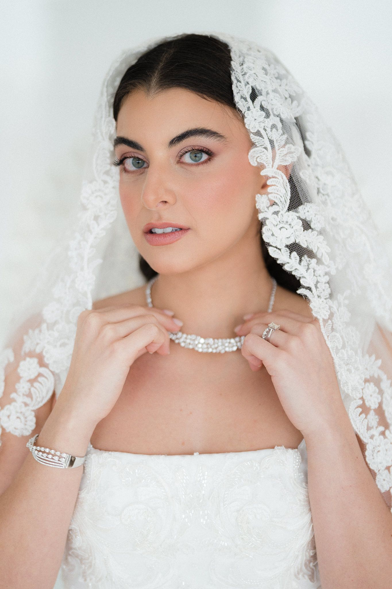 Close-up details of bridal accessories including lace veil and crystal jewelry.
