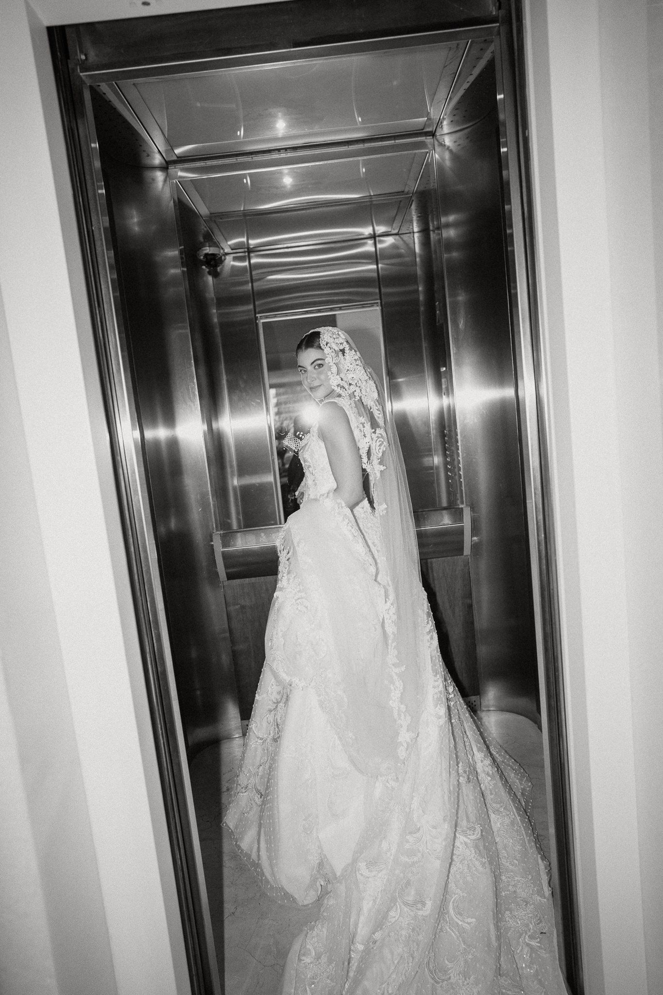 A series of elegant white wedding dresses displayed in a row along a mirrored hallway.