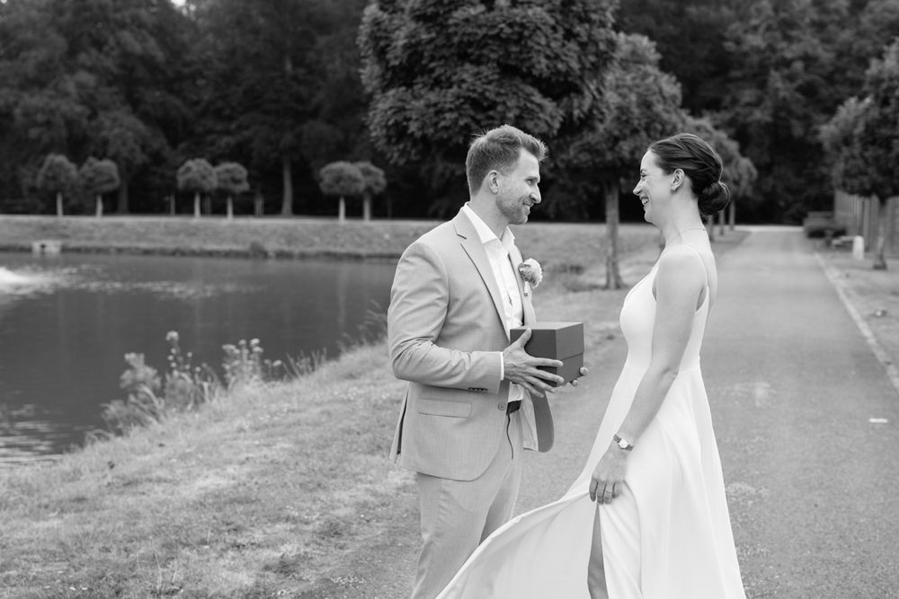 A couple in formal wedding attire walks and dances together in a garden setting during their celebration.
