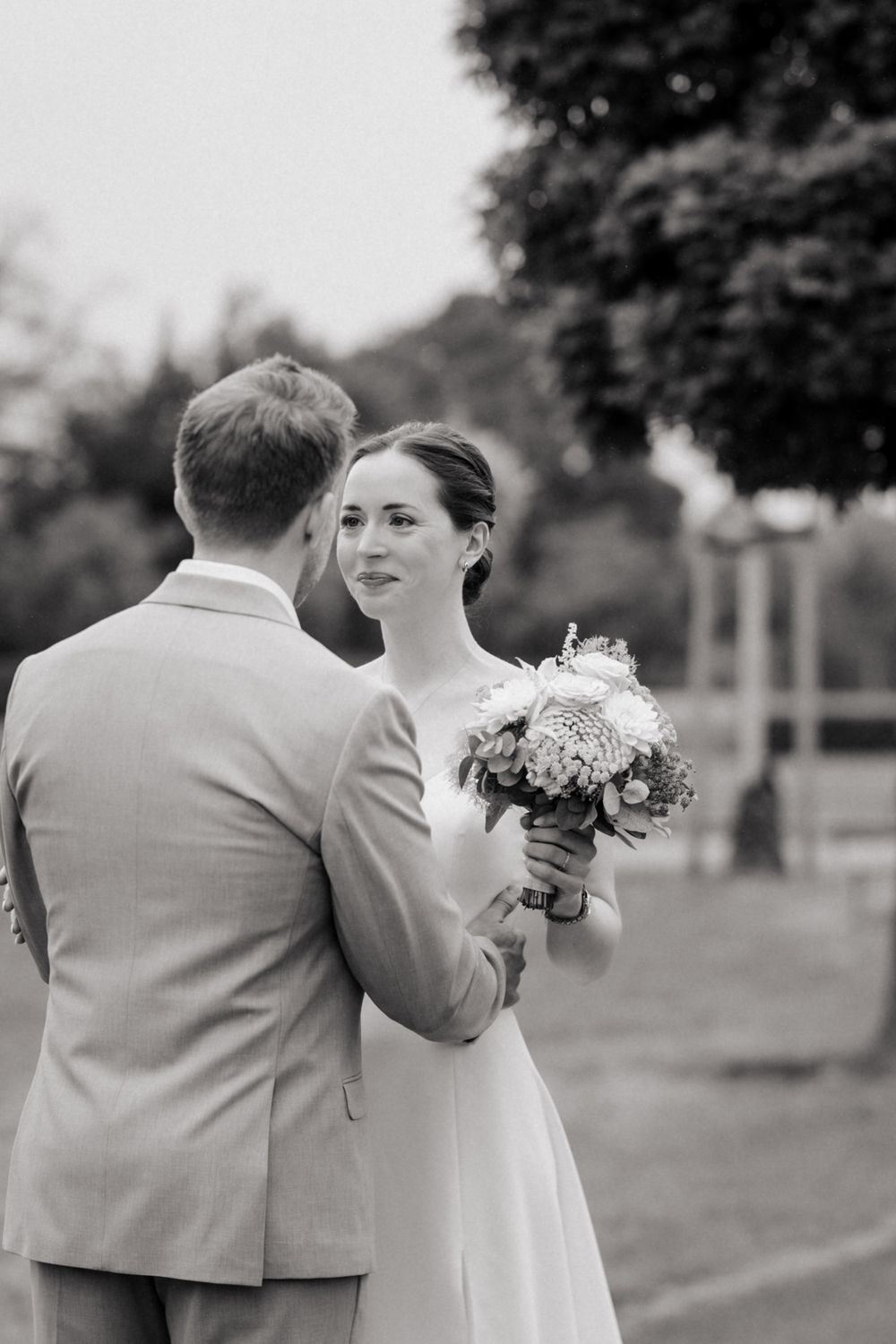 A black and white photo series shows a couple walking together in formal attire at an outdoor wedding venue.
