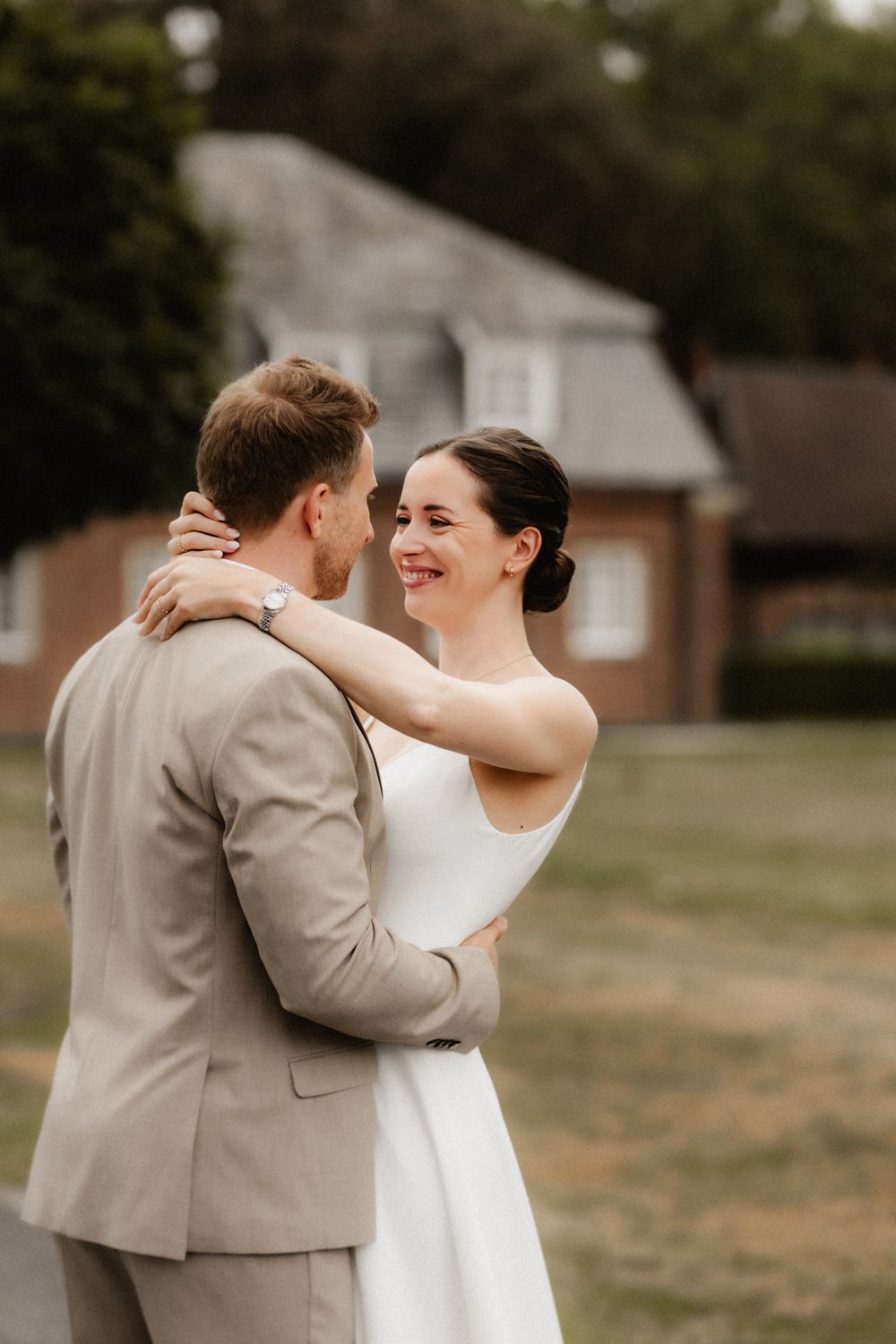 A couple shares an intimate moment during their outdoor wedding photoshoot in a grassy field.