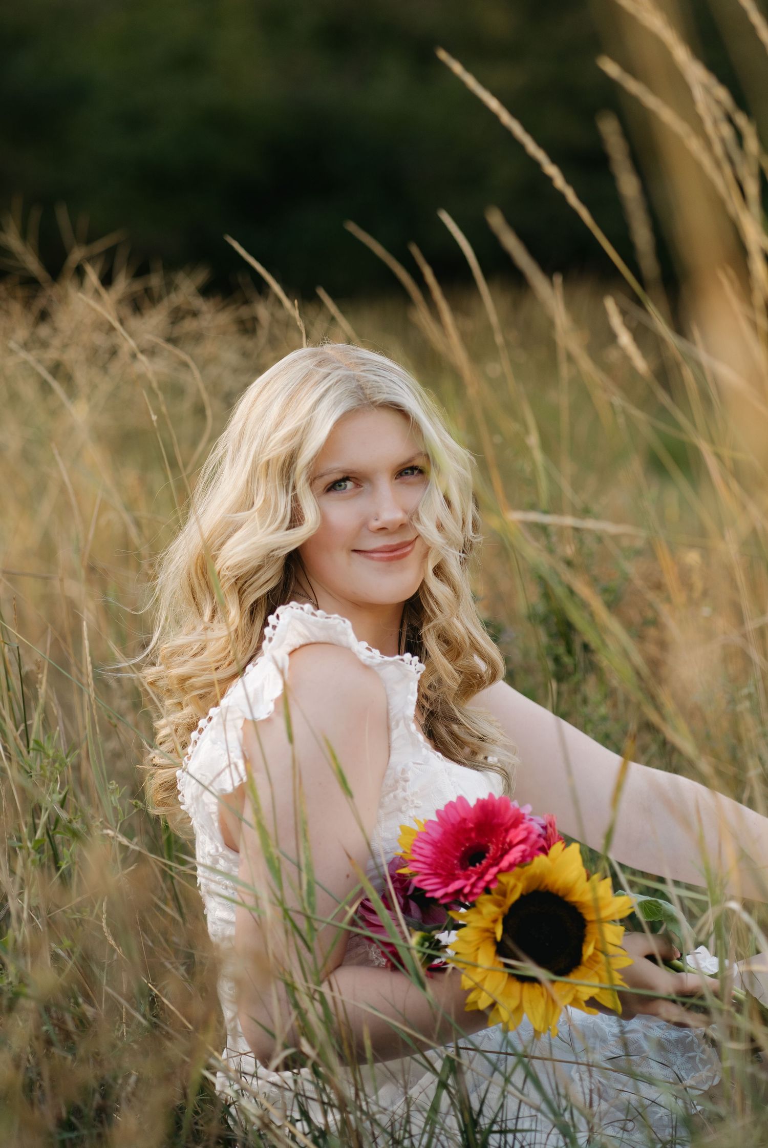 Person in white dress poses with sunflowers in golden mountain grass. Leavenworth, WA