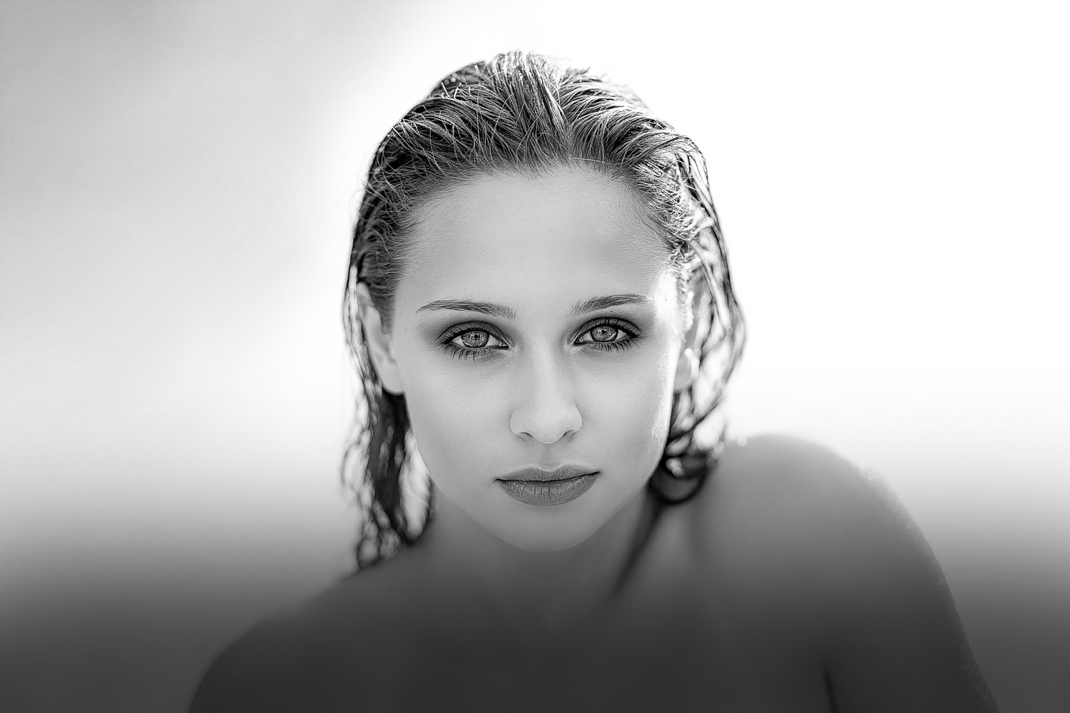 Black and white portrait of a woman with wet hair and striking eyes gazing directly at the camera.