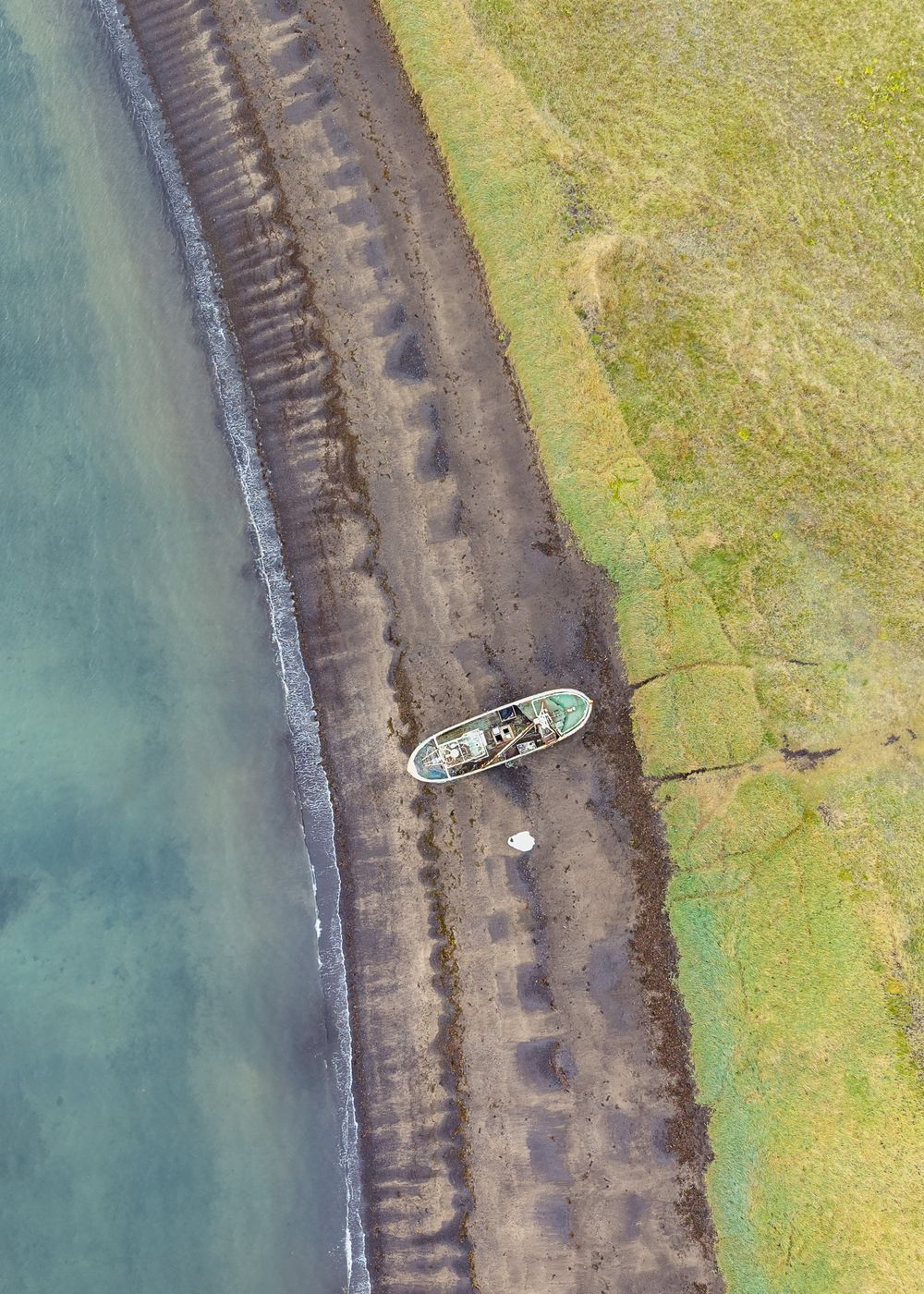 Aerial view of a small boat navigating along a winding river channel through green marshland.