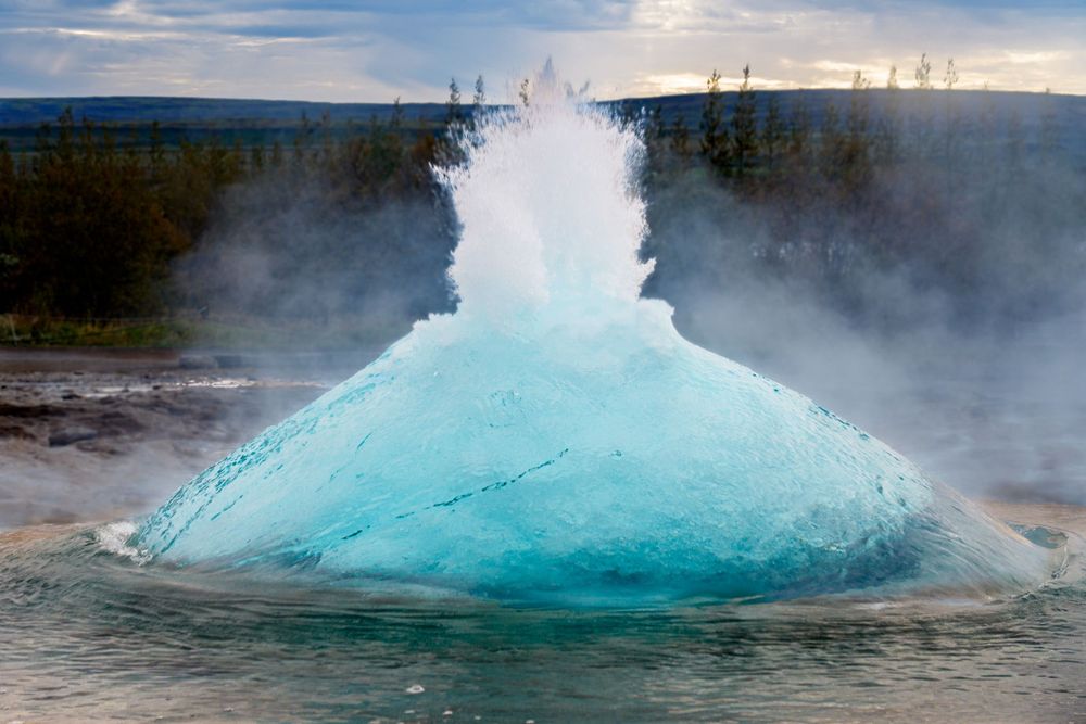 Turquoise hot spring erupts with a powerful burst of water and steam at Yellowstone National Park.