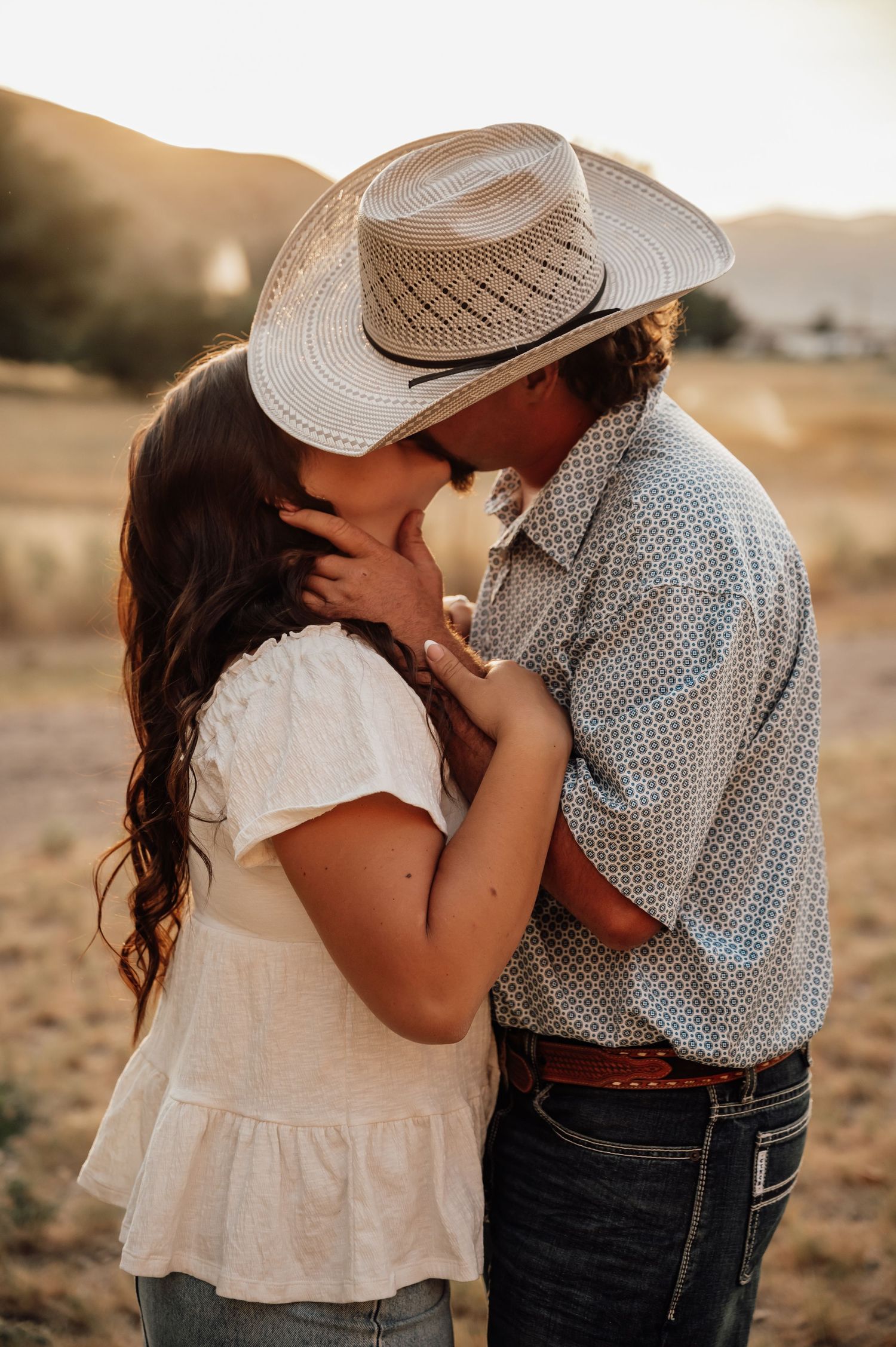 Two people in western attire sharing an intimate moment at sunset.