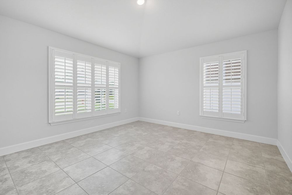Bright white interior room with plantation shutters and gray tile flooring showcases modern minimalist design.