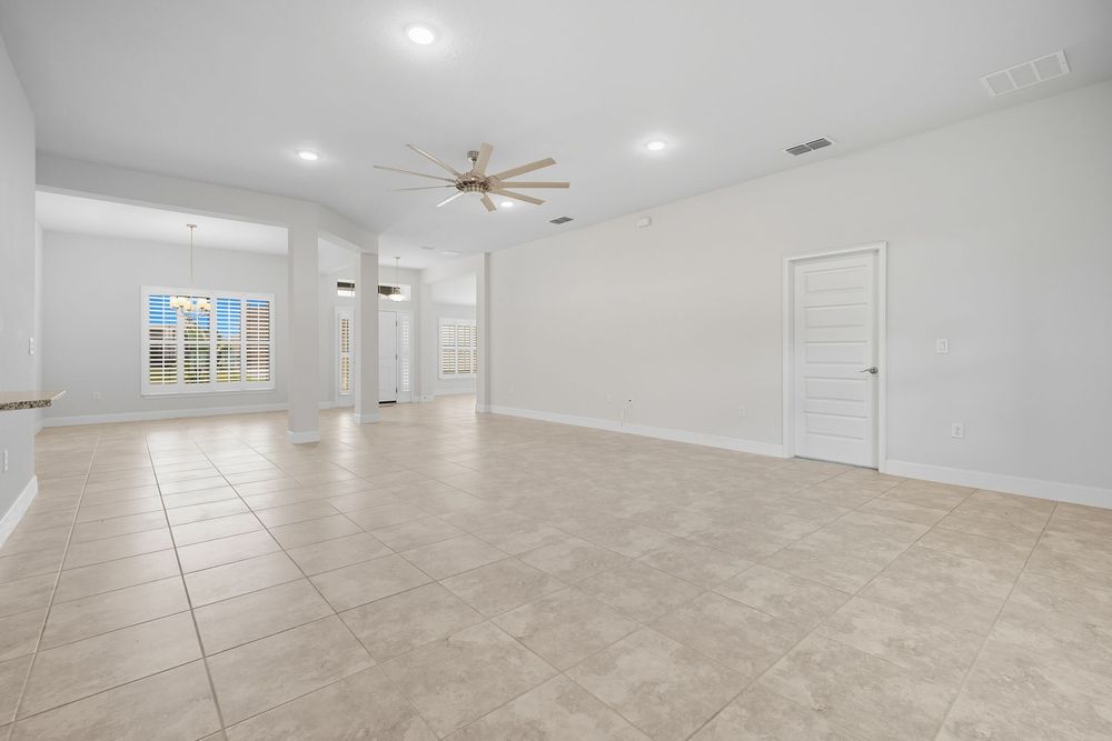 Modern open concept living room with light tile flooring, recessed lighting, and ceiling fan in new construction home.