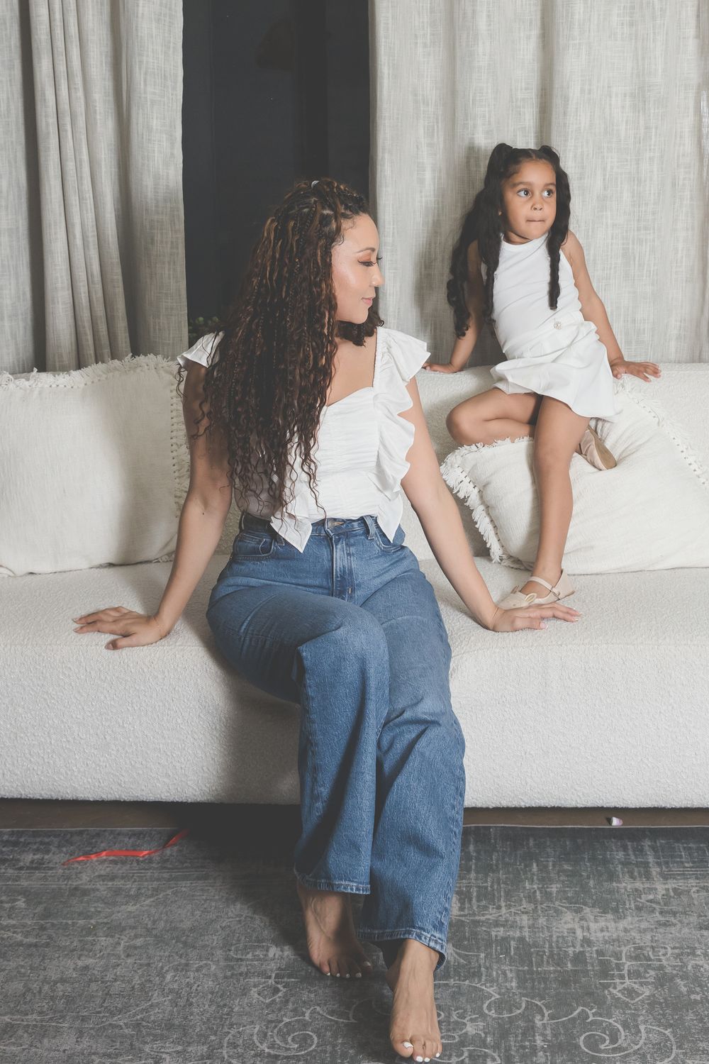 Casual lifestyle portrait on white couch with matching white outfits.