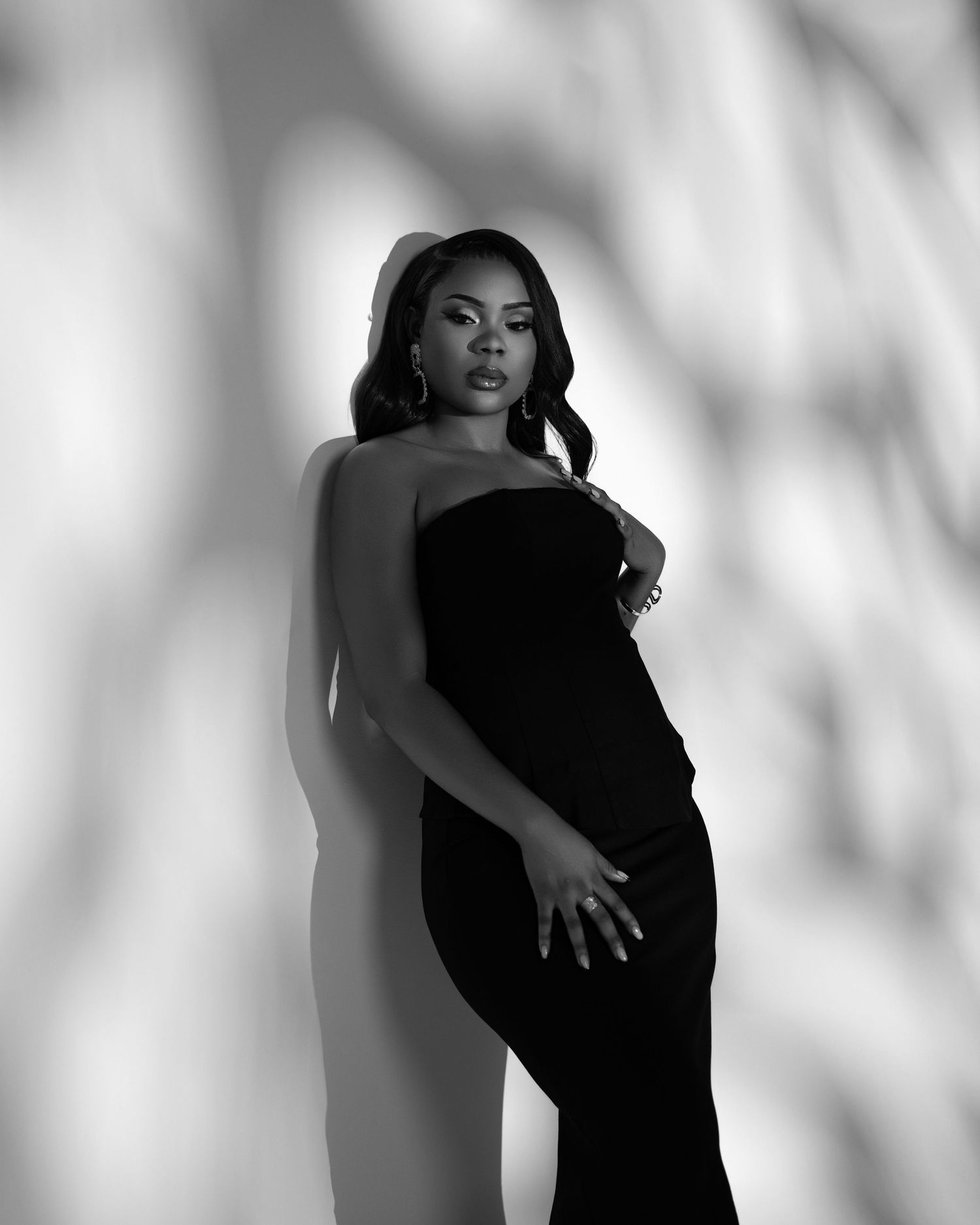 A figure in a sparkling silver gown poses elegantly with silver balloons against a dramatic monochrome backdrop.