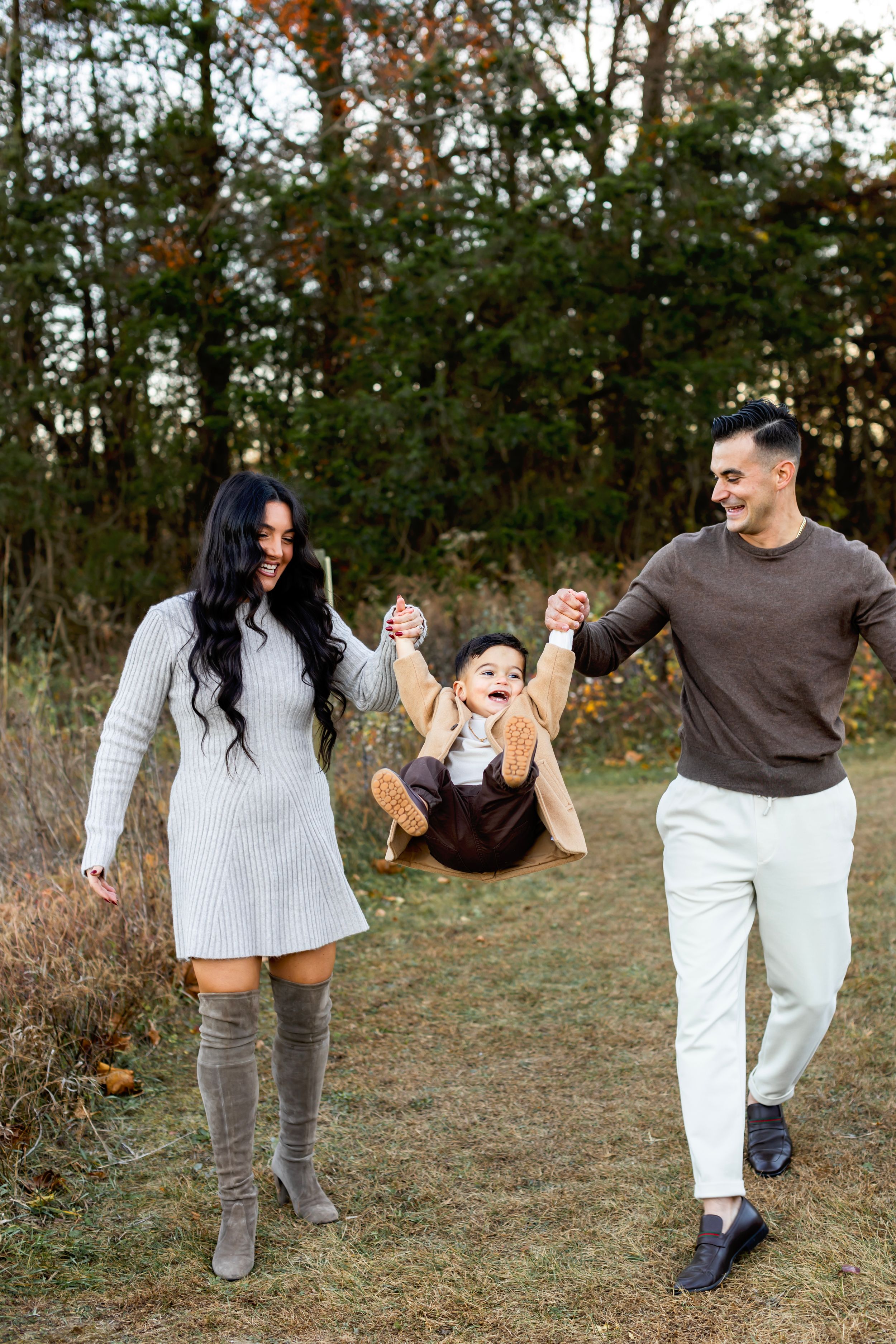 A couple playfully dancing and spinning together in a grassy outdoor field at sunset.