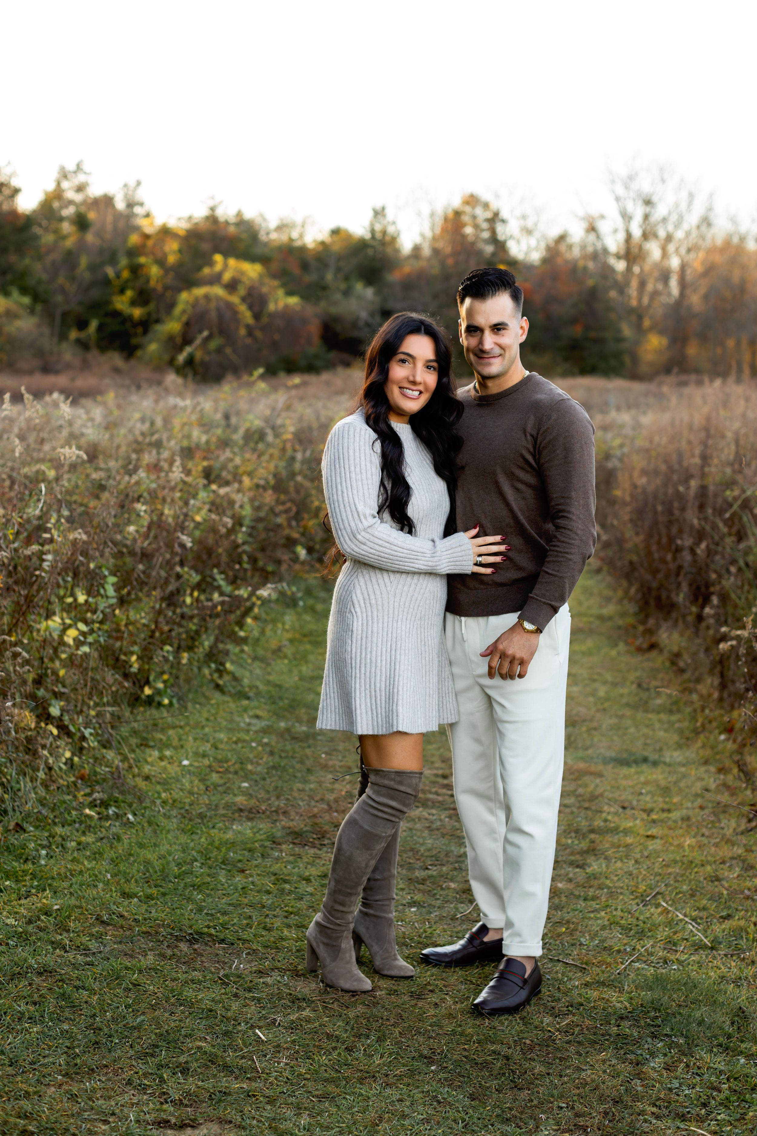 A couple embracing and laughing together in a rustic outdoor setting during autumn.