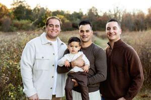 A group in coordinated brown and white outfits poses together outdoors during golden hour in a natural setting.