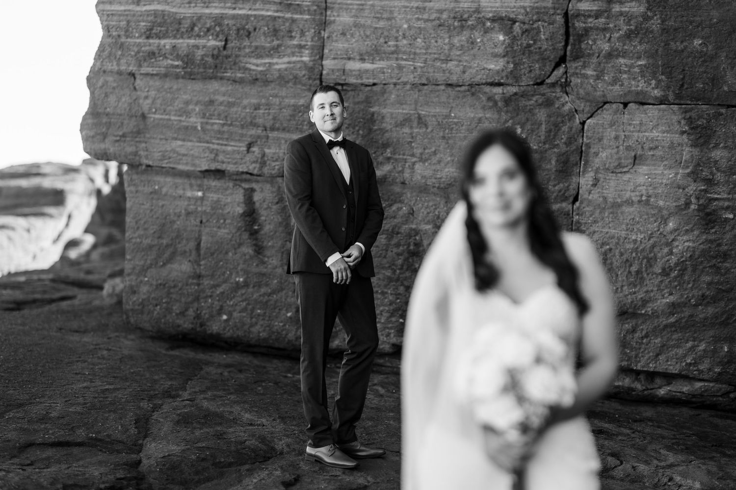 A black and white wedding photo collage showing a couple posing against a rustic stone wall backdrop.