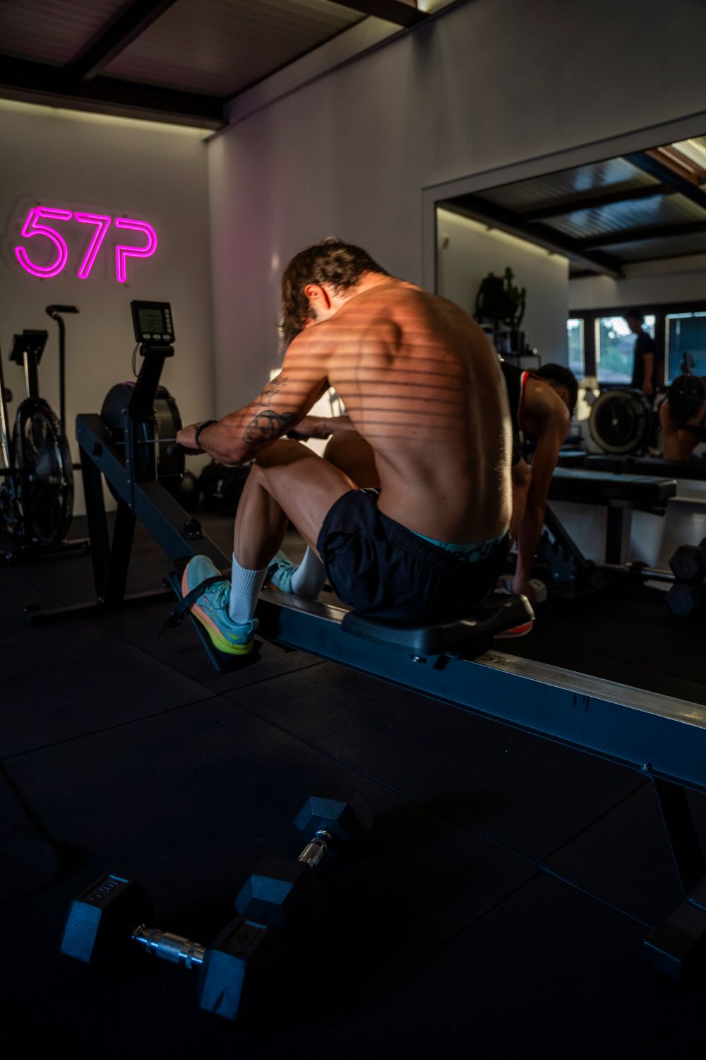 A man performing a box jump in a gym with pink neon "STP" lighting; dynamic action photography for modern fitness centers.