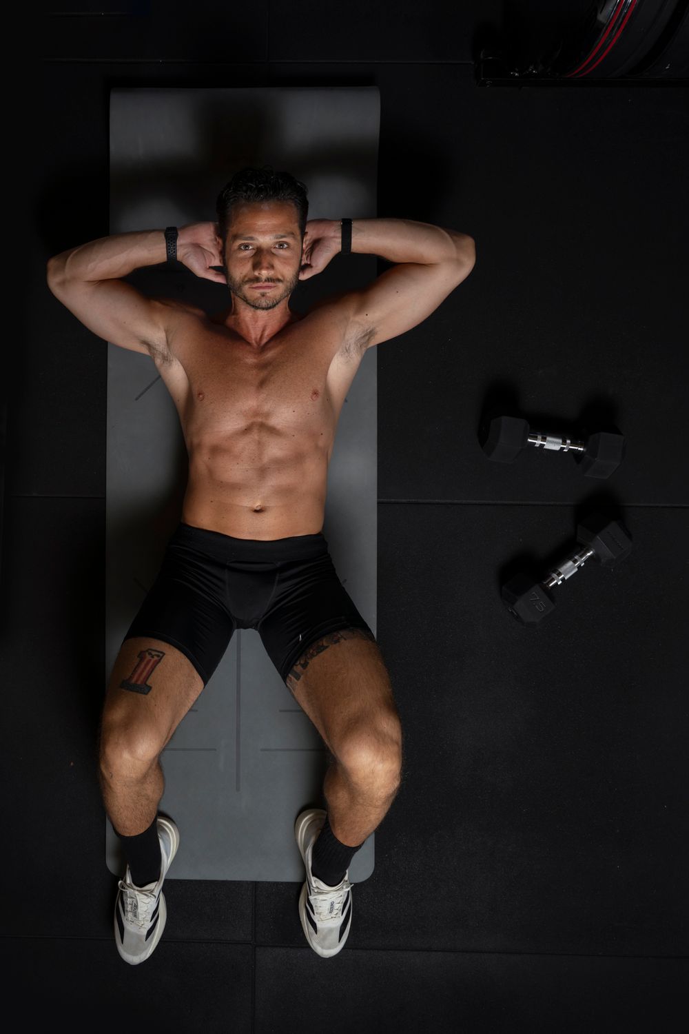 Overhead shot of a man performing abdominal crunches on a mat; core strength and conditioning photography for fitness apps.